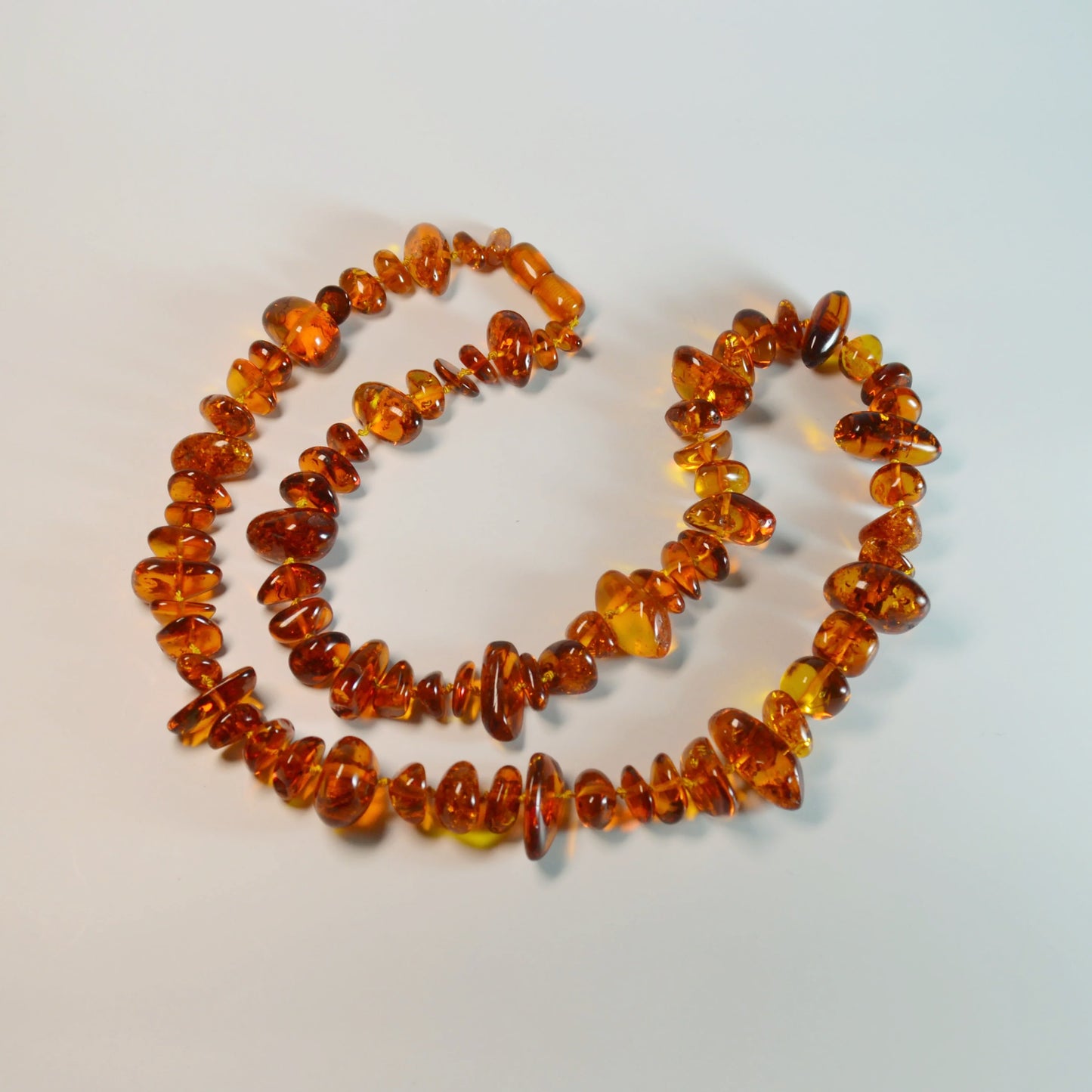 Baltische Bernstein Kette 70 cm – Nahaufnahme liegend, hochwertiger Drehverschluss und natürliche Bernstein-Struktur erkennbar.