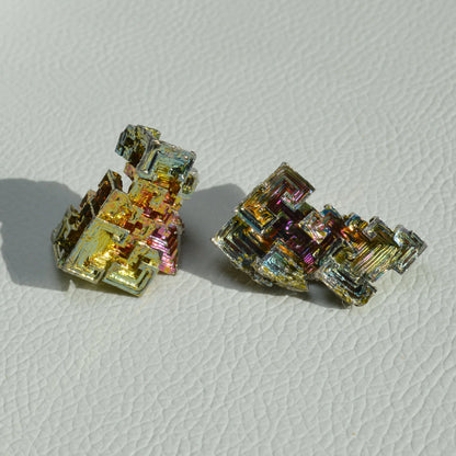 Bismut-Kristall mit regenbogenartiger Farbgebung in Gold, Rosa, Lila, Blau und Grün.
