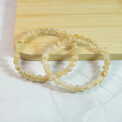Gold Rutilquarz Armband mit 6mm Perlen, zwei elastische Armbänder um naturbedingte Unterschiede zu zeigen.