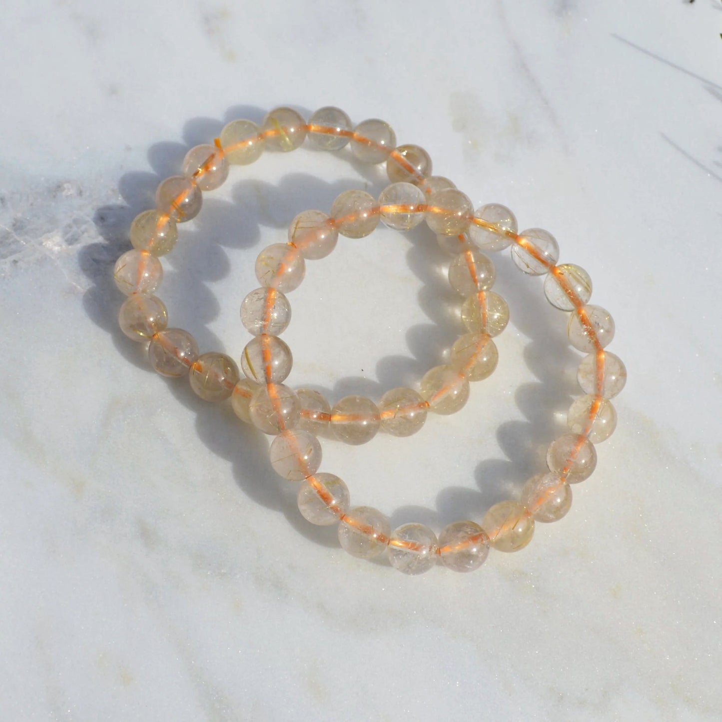 Gold Rutilquarz Armband mit 8mm Perlen, zwei elastische Armbänder um naturbedingte Unterschiede zu zeigen.
