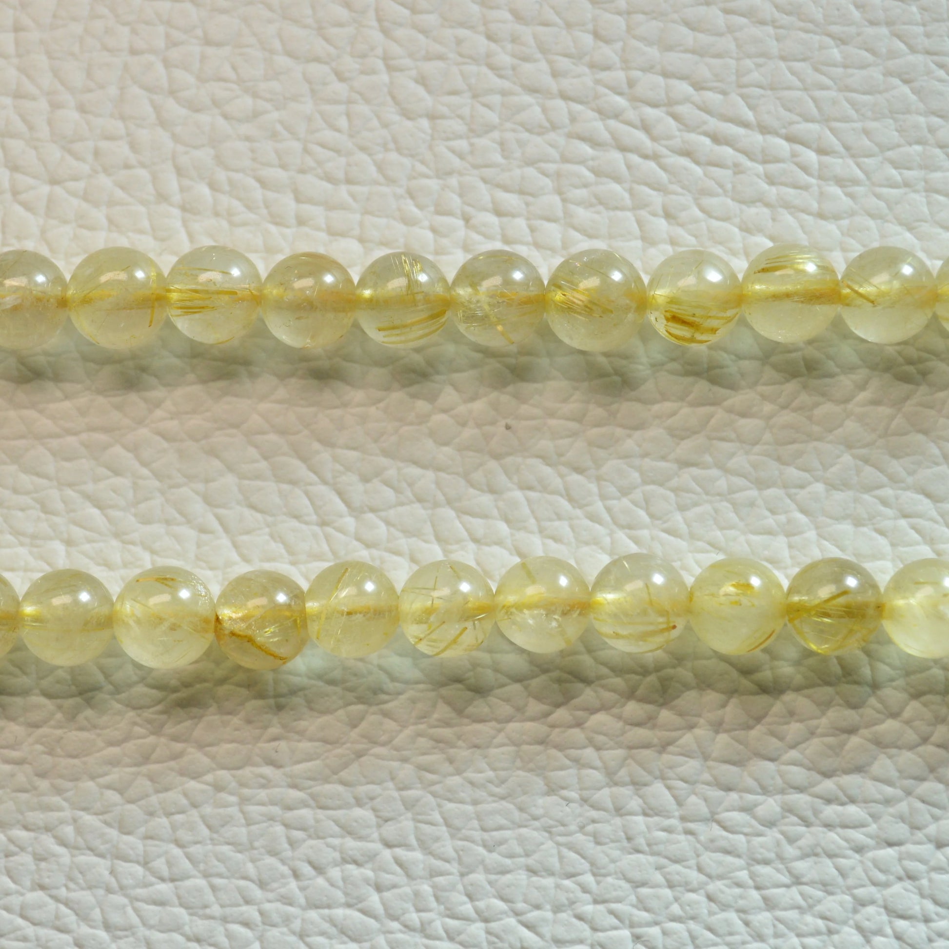 Gold Rutilquarz Perlenkette aus 6mm Naturstein – Kristallschmuck mit Metallverschluss und goldenen Rutilnadeln. Nah.