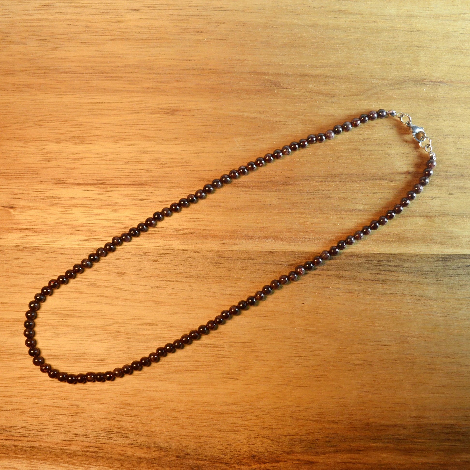 Granat Perlenkette aus 4mm Naturstein – Kristallschmuck mit Metallverschluss. Gesamtansicht.