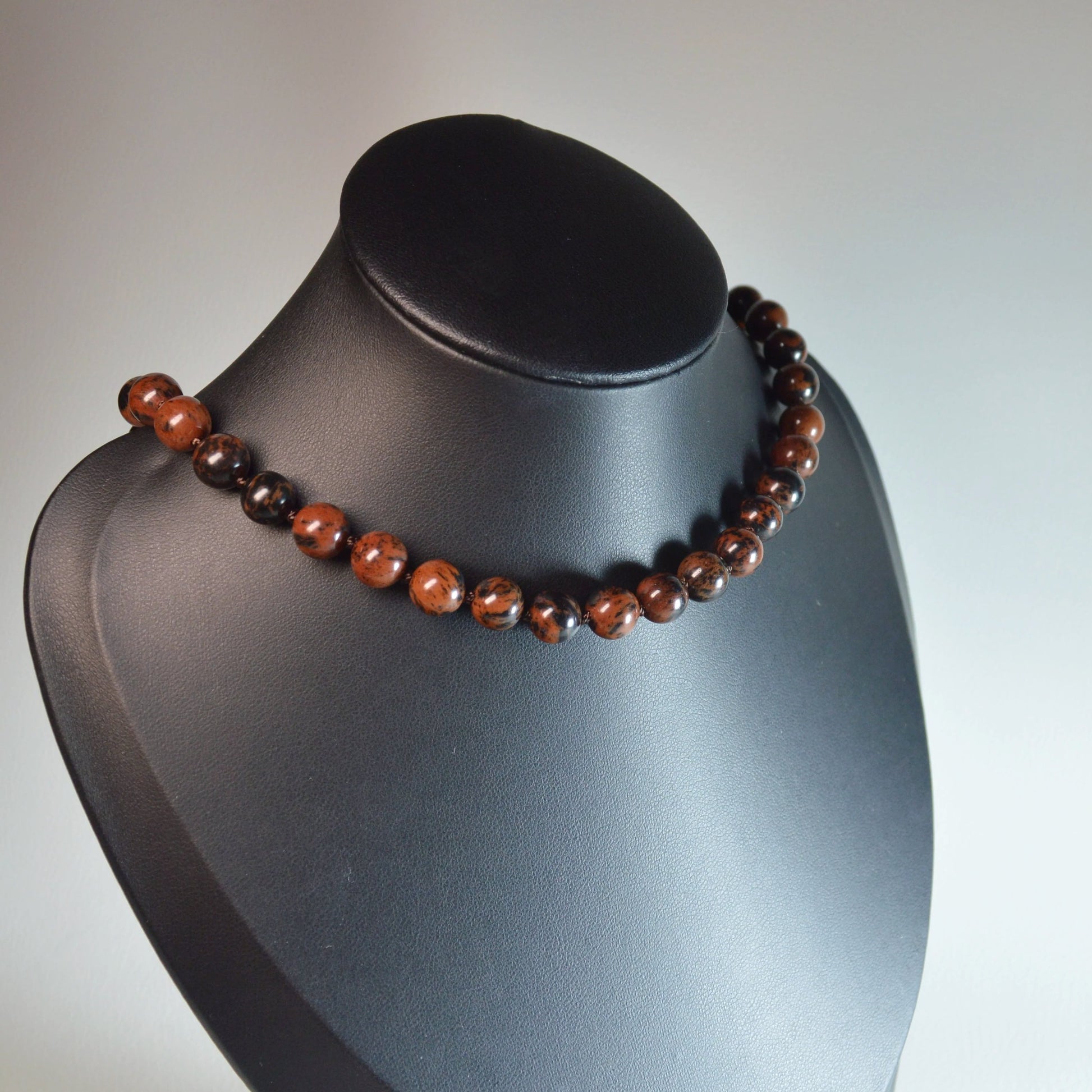 Handgemachte Mahagoni-Obsidian Halskette mit klaren Kristallperlen – hochwertiger Naturstein-Schmuck auf Büste.