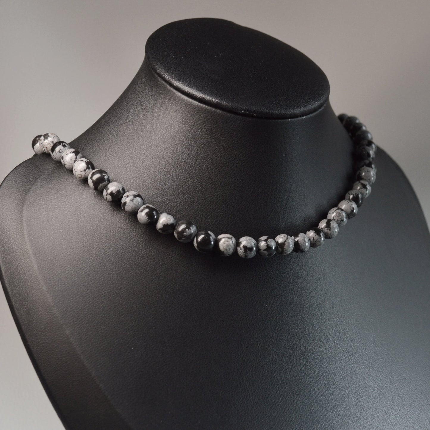 Handgemachte Schneeflocken-Obsidian Halskette mit 6mm Kristallperlen – hochwertiger Naturstein-Schmuck auf Büste.