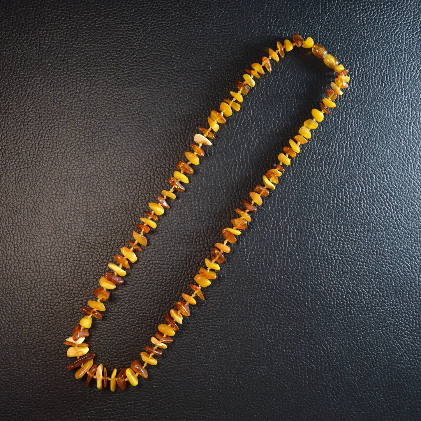 Mehrfarbige Bernstein Kette 55 cm – Gesamtansicht liegend, natürlicher Glanz der Steine und Drehverschluss erkennbar.