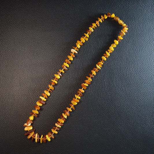 Mehrfarbige Bernstein Kette 55 cm – Gesamtansicht liegend, natürlicher Glanz der Steine und Drehverschluss erkennbar.