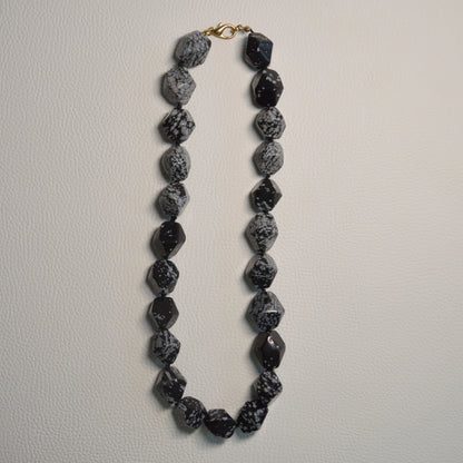 Schneeflocken-Obsidian Perlenkette aus 15-20mm facettierten Naturstein Nuggets – Kristallschmuck mit goldenem Metallverschluss. Gesamtansicht.