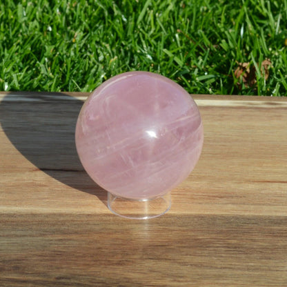 Seitenansicht einer Sternrosenquarz Kugel, die die charakteristischen Rosafärbungen und Texturen zeigt.